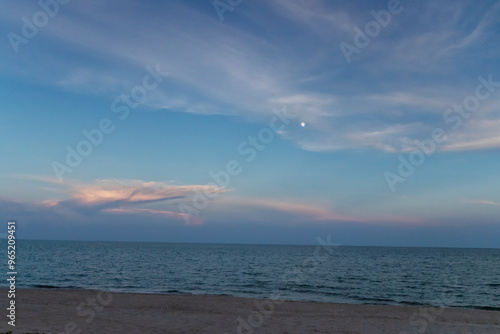 A serene twilight sky over the calm ocean, with soft clouds and a hint of stars illuminating the evening. photo