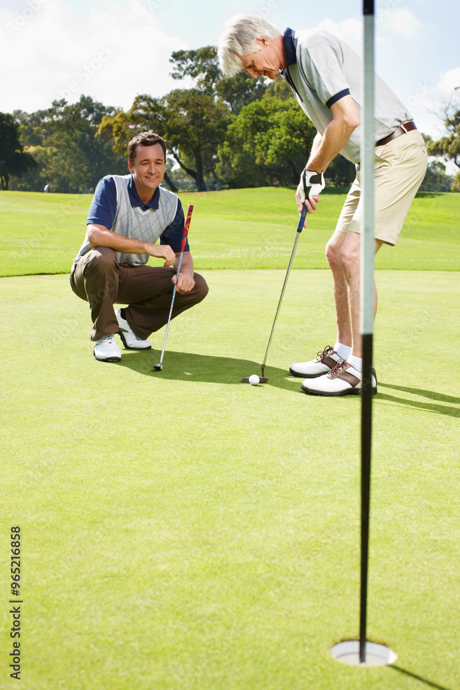 Fototapeta premium Coaching, hole and men on golf course together for teamwork, outdoor fun and fitness competition at club. Sports, senior father and son on green for partnership, bonding and support in healthy hobby.