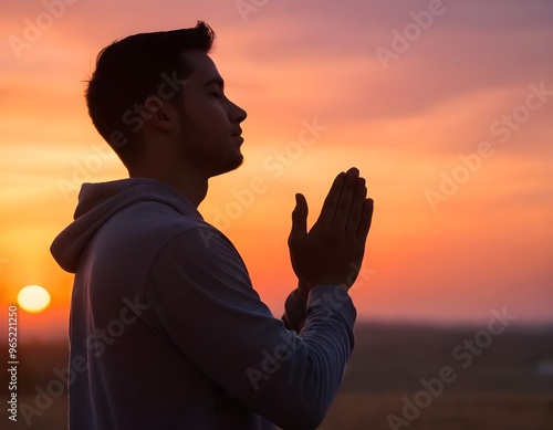 Silhouette of a person praying at sunset with vibrant skies and mountains in the background