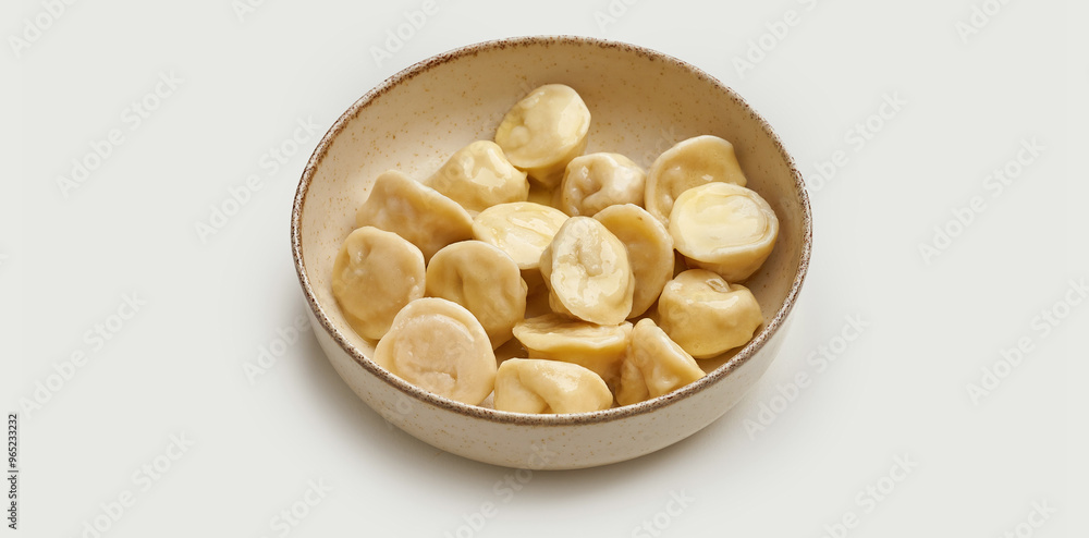 A bowl of freshly cooked dumplings is presented on a beige plate against a clean white background. A bowl of freshly cooked dumplings is presented on a beige plate against a clean white background.