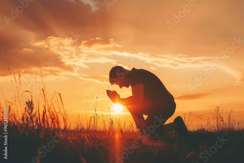 Christian prayer. Man on his knees praying on sunset background. Kneeling prayer to God. Worship and praise photo