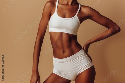 woman's toned midsection against a beige background, wearing a white undergarment or sportswear