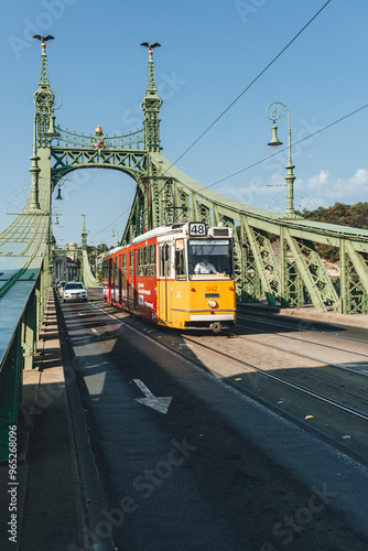 beautiful contrasting yellow famous tram passing by the green bridge in the morning city