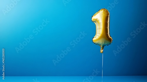 This bright blue background showcases a gleaming golden balloon with the numeral one, ideal for marking a one-year anniversary and providing plenty of space for custom messages. photo