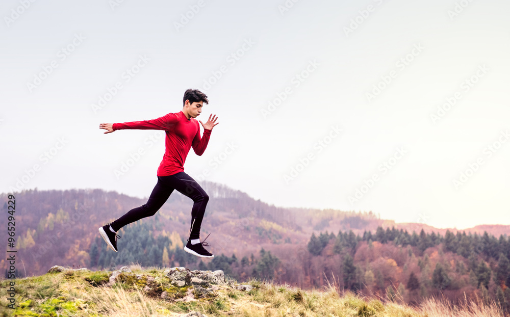 Male runner jumping over rock, jogging in nature on dirt running trail. Morning running training for young man. Male runner jumping over rock, jogging in nature on dirt running trail. Morning running training for young man.
