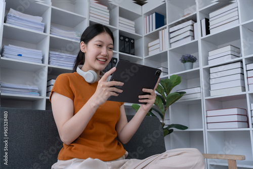 woman relaxes at home on the sofa, using her tablet computer for entertainment or work, enjoying a comfortable and peaceful moment in her living space