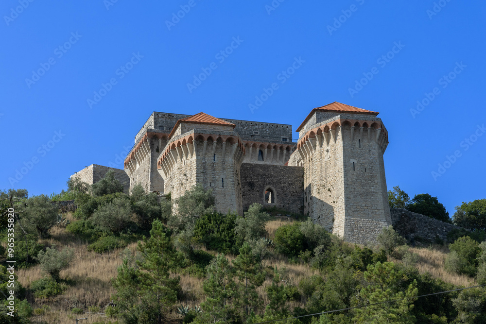 View of Ourem Castle from the valley with a blue sky. The valley is covered with trees and plants View of Ourem Castle from the valley with a blue sky. The valley is covered with trees and plants