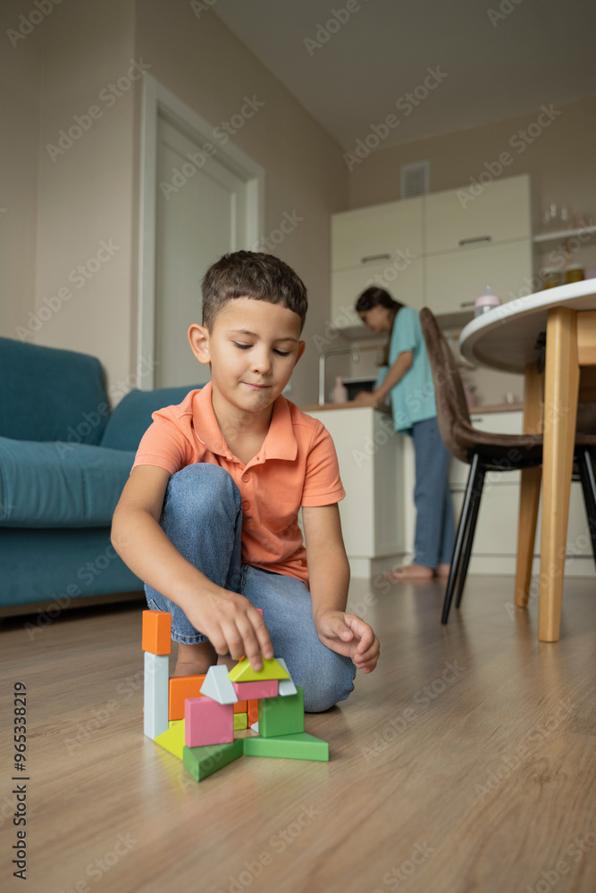 Playful boy sitting on floor and playing with blocks at home Playful boy sitting on floor and playing with blocks at home
