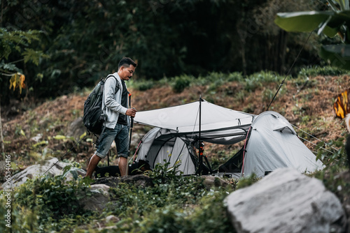 Hikers walk on rocks with dog in the stream flowing from the waterfall bact to his tent in hill. photo