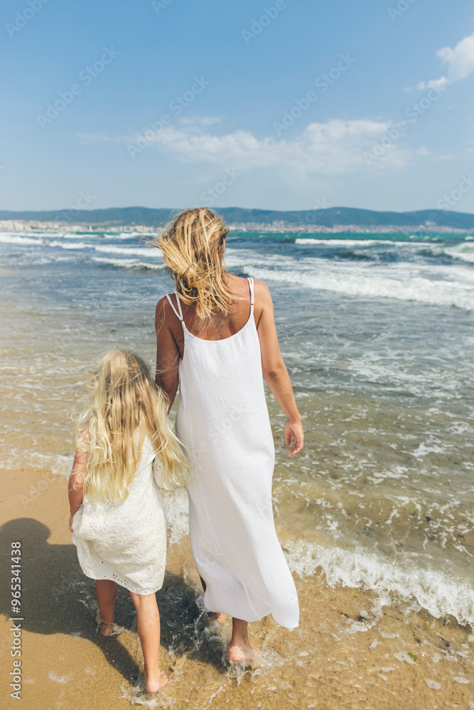 Mother and daughter walking at beach on sunny day Mother and daughter walking at beach on sunny day