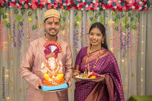 Happy Indian couple Family celebrating Lord Ganesh Festival, Worshipping God together in traditional wear at home, seeking blessings from Lord Ganesha, Pune, Maharashtra, India. photo