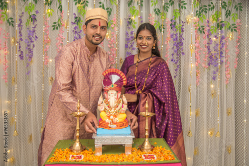 Happy Indian couple Family celebrating Lord Ganesh Festival, Worshipping God together in traditional wear at home, seeking blessings from Lord Ganesha, Pune, Maharashtra, India. photo