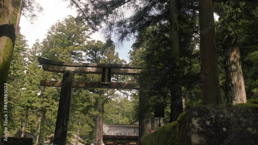 Wide panning shot of a stone tori gate in the midst of countryside Japan with nice light shining through Wide panning shot of a stone tori gate in the midst of countryside Japan with nice light shining through