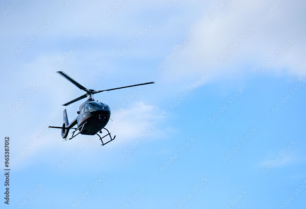 Helicopter flying through a clear blue sky with fluffy white clouds. Helicopter flying through a clear blue sky with fluffy white clouds.