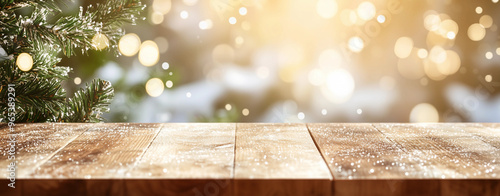 Christmas background with close up of wooden table with snowy christmas trees and sparkling lights in the background
