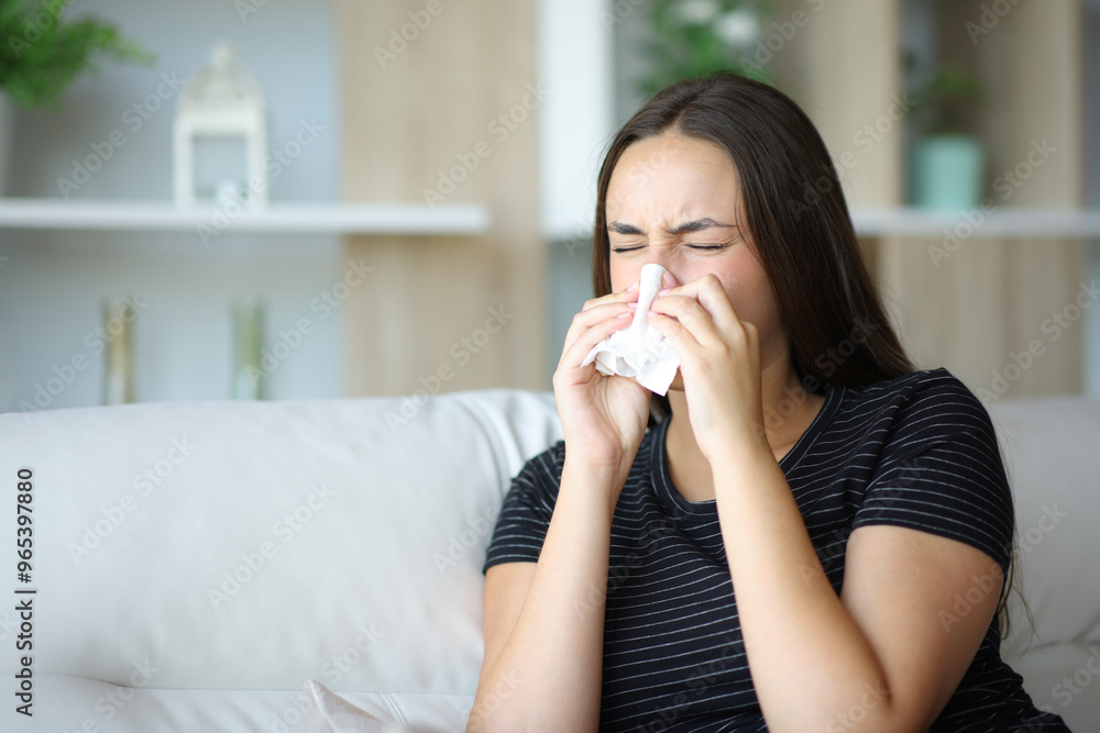 Ill woman sneezing using tissue at home Ill woman sneezing using tissue at home