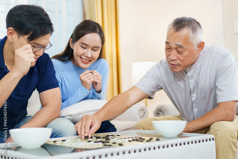 Son and daughter enjoy playing Go Board Game with their father in free time weekend. Son and daughter enjoy playing Go Board Game with their father in free time weekend.