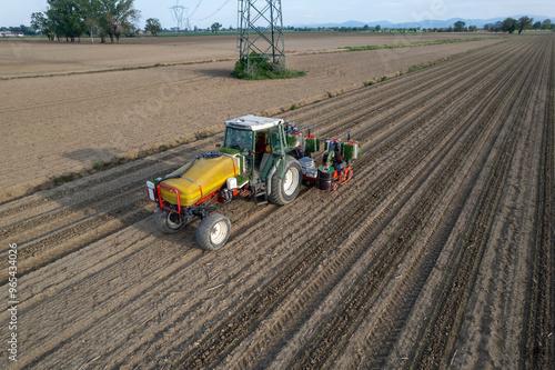 Aerial view of old tractor and semi Automatic tomato planter machine working in a field