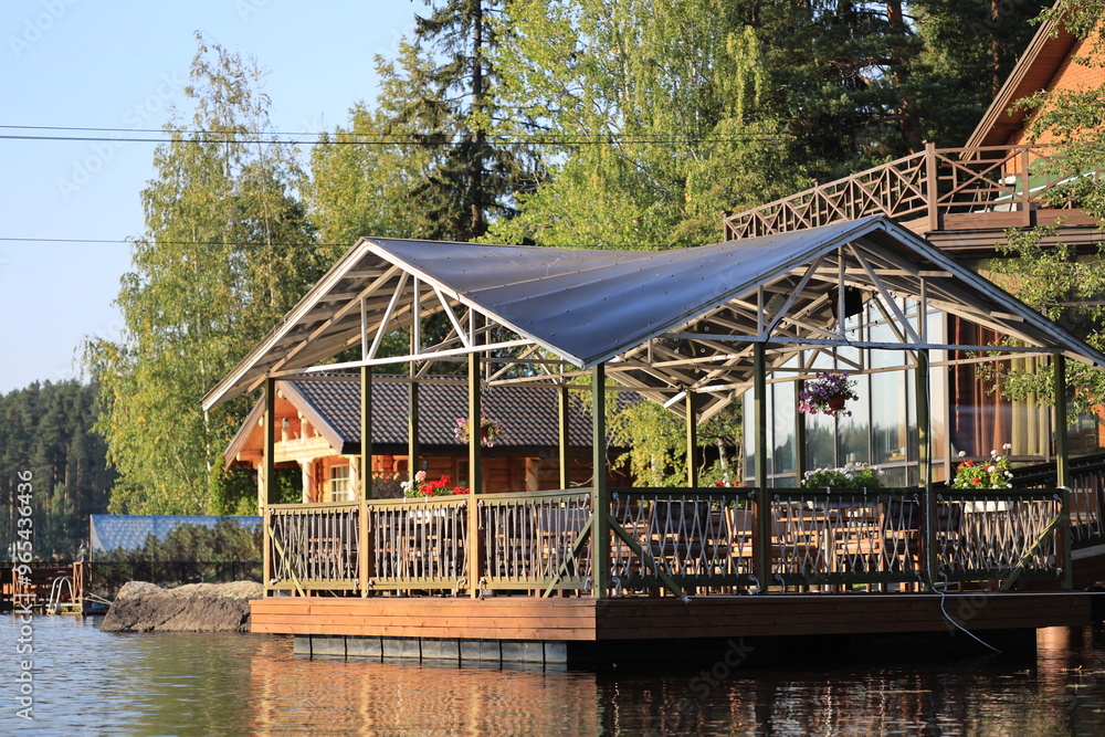 A residential houseboat moored at a wooden dock, surrounded by calm water and lush vegetation. A residential houseboat moored at a wooden dock, surrounded by calm water and lush vegetation.