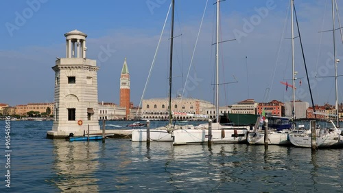 City skyline of Venice in Italy from San Giorgio Maggiore island in the Venetian Lagoon with St. George Lighthouse and sailing boats in the marina.