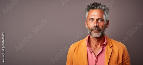 A man with a beard and gray hair is wearing a bright orange jacket