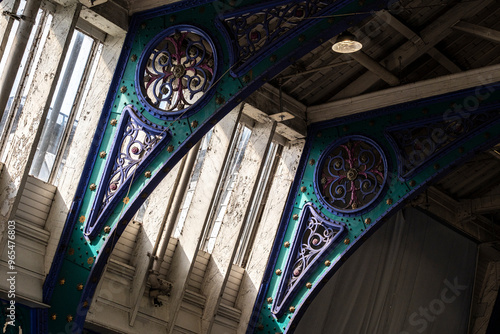 An intriguing shot of a historical building's interior featuring colorful, ornate metal beams, beautifully blending old architectural design with detailed craftsmanship.