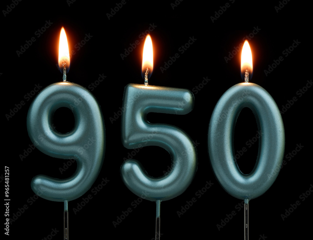 Burning blue birthday candles on black background, number 950 Burning blue birthday candles on black background, number 950