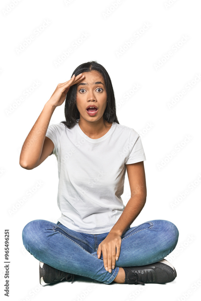 Latina sitting on floor in studio shouts loud, keeps eyes opened and hands tense. Latina sitting on floor in studio shouts loud, keeps eyes opened and hands tense.