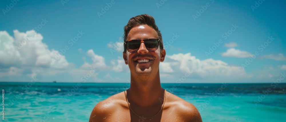 A smiling man in sunglasses stands against the breathtaking backdrop of a vibrant blue ocean under a bright sky. A smiling man in sunglasses stands against the breathtaking backdrop of a vibrant blue ocean under a bright sky.