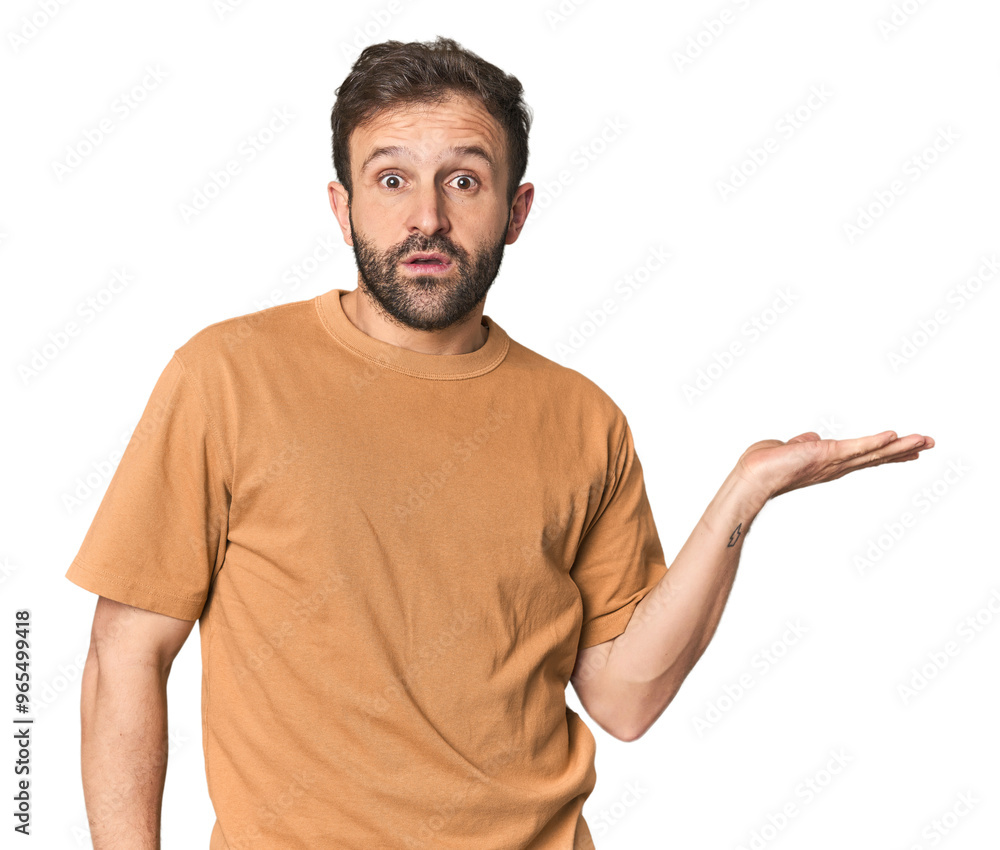 Studio portrait of young Hispanic male impressed holding copy space on palm. Studio portrait of young Hispanic male impressed holding copy space on palm.