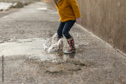 child splashing a puddle of rain