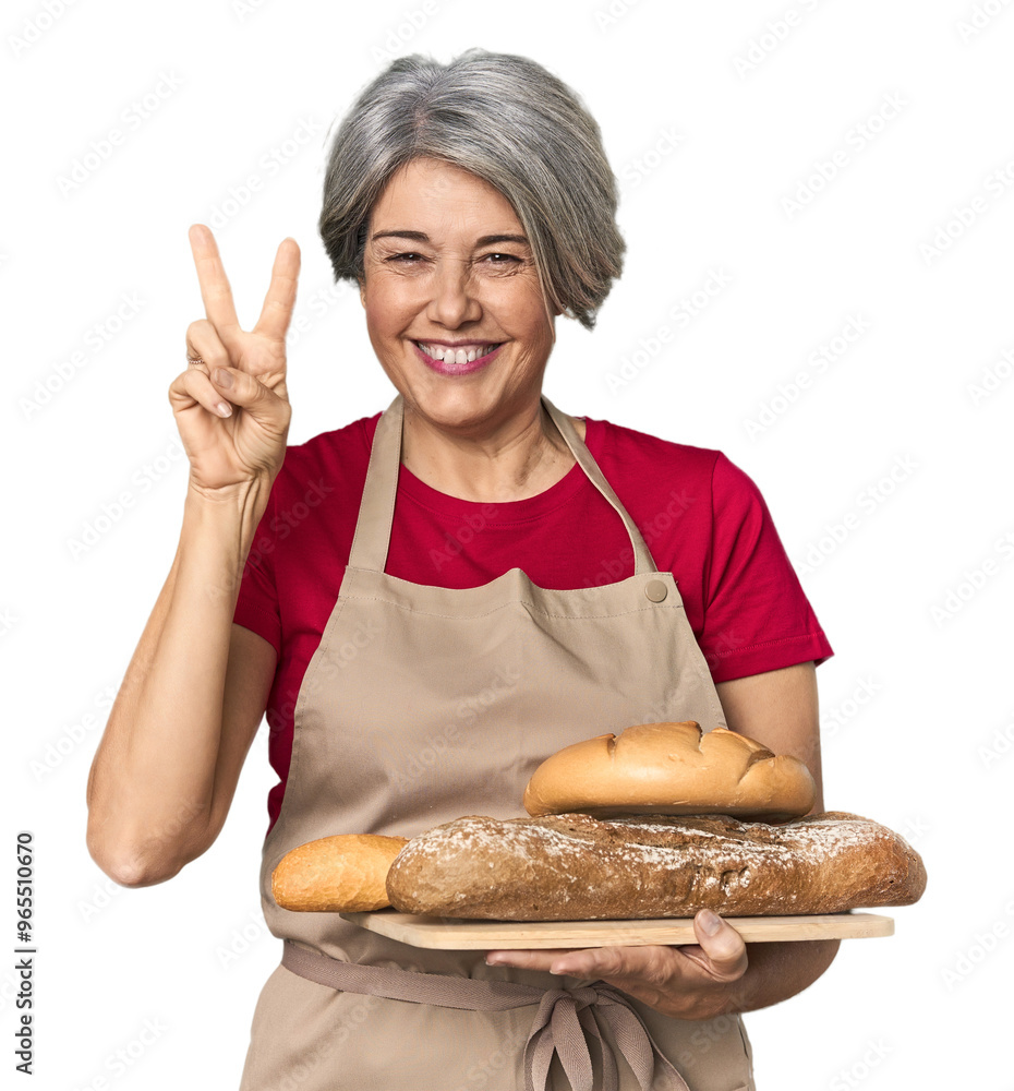 Caucasian mid-age baker with bread loaves showing number two with fingers. Caucasian mid-age baker with bread loaves showing number two with fingers.