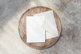 Blank 5x7 card mockup with envelope on wooden tray and stone background top view