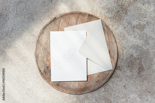 Blank 5x7 card mockup with envelope on wooden tray and stone background top view photo