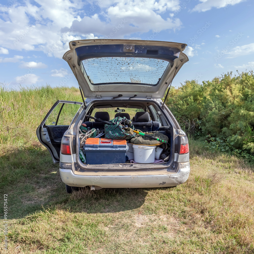 open trunk of car with fishing gear in nature open trunk of car with fishing gear in nature