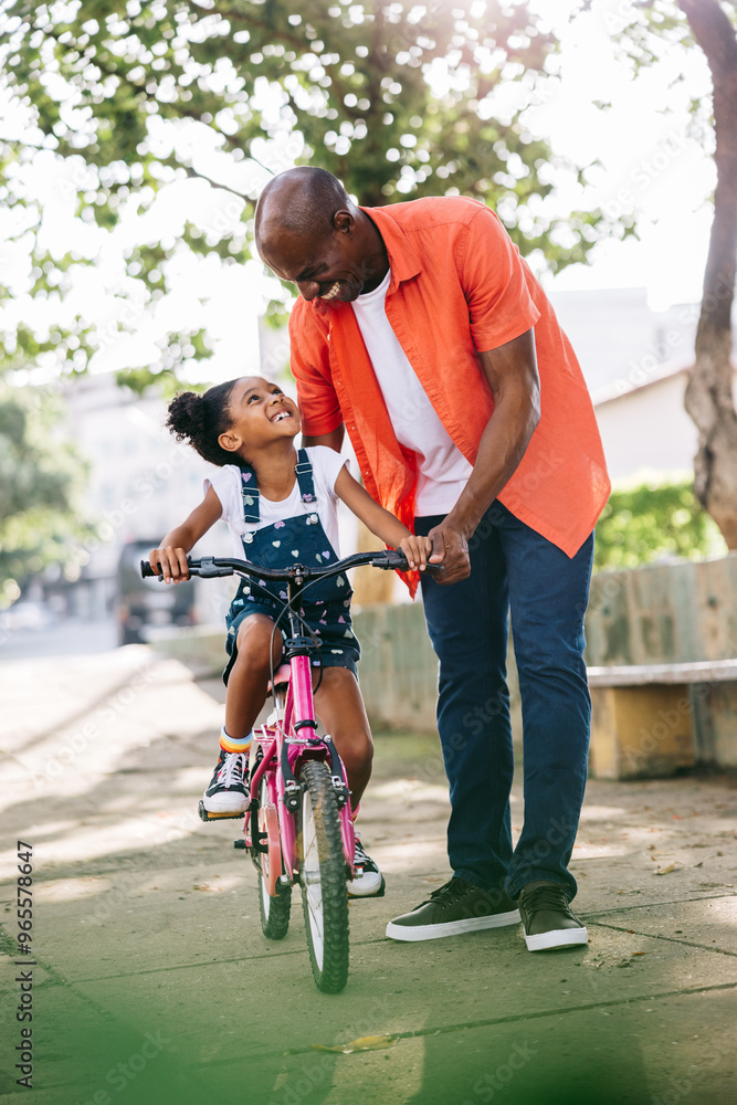 Father teaching daughter how to ride a bike in the park Father teaching daughter how to ride a bike in the park