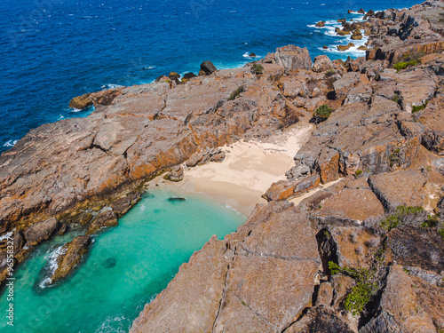 Majestic shoreline where rough rocks meet calm turquoise waters, offering a dramatic and picturesque coastal setting.