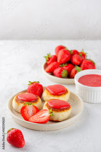 Vegan cheesecakes with strawberries, syrniki, cheese pancakes made from tofu and cashews in a plate. Sugar, lactose and gluten free. Vertical orientation.