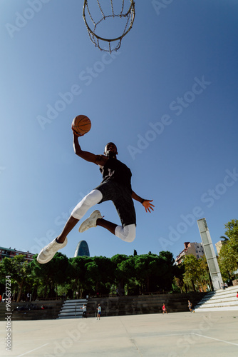 Fotografi Street basketball player making a powerful slam dunk on the court - Athletic mal