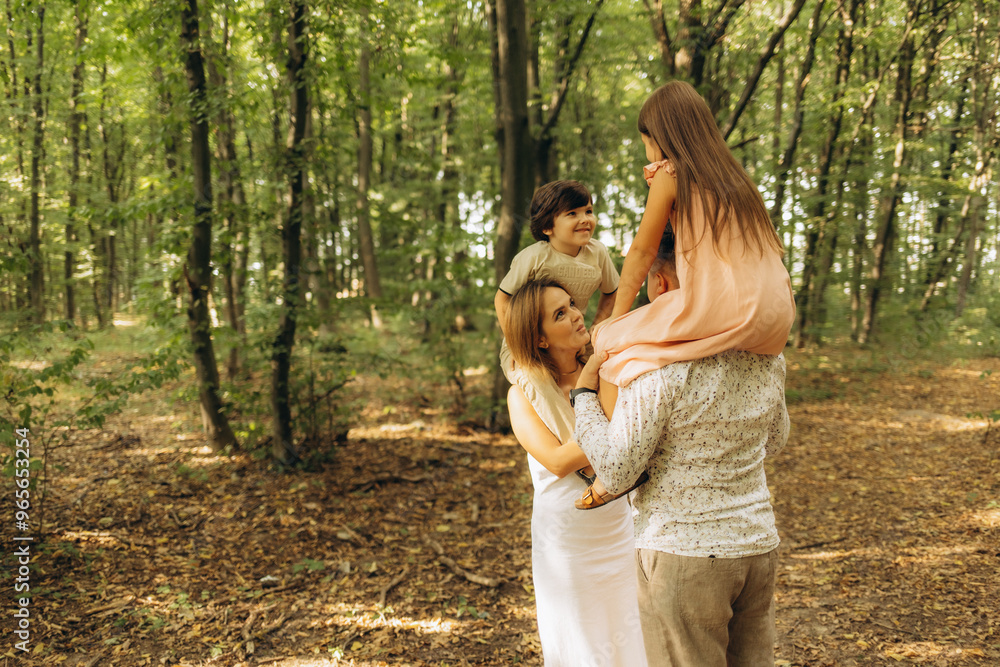 A young family walks in the autumn forest. Happy mum, dad, son and daughter A young family walks in the autumn forest. Happy mum, dad, son and daughter