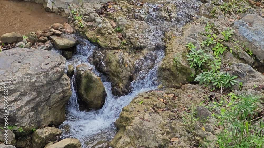 Clear water flows from the mountains to waterfalls between the rocks. Clear water flows from the mountains to waterfalls between the rocks.
