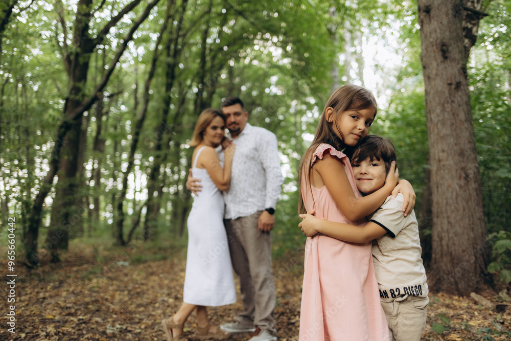 Dad hugs mum and brother hugs sister in the park Dad hugs mum and brother hugs sister in the park
