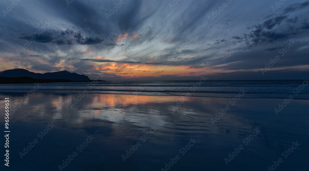 Naklejka premium Wide angle view of Sunset in cloudy sky over the calm sea. the reflection of the sunset on a pristine sandy beach. Lofoten Islands, Northern Norway.