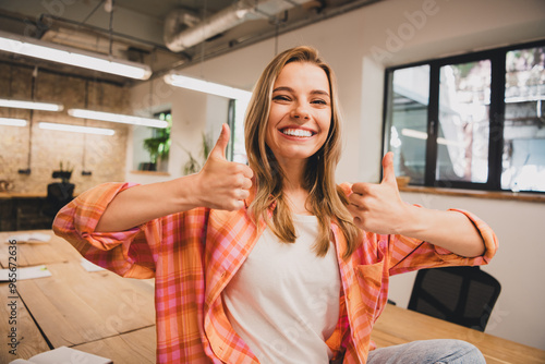 Portrait of pretty young office worker woman show thumb up loft interior business center indoors photo