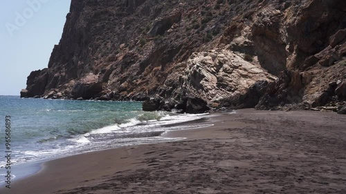 Gimbal dolly shot of secluded black sand beach on Portmán Bay coast, near La Unión, Spain. Walking on an empty beach surrounded by high cliffs with no people 4K professional Film Camera ProRes HQ