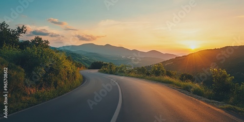 A scenic view of a winding road at sunset, surrounded by lush greenery and mountains, perfect for travel and nature themes.