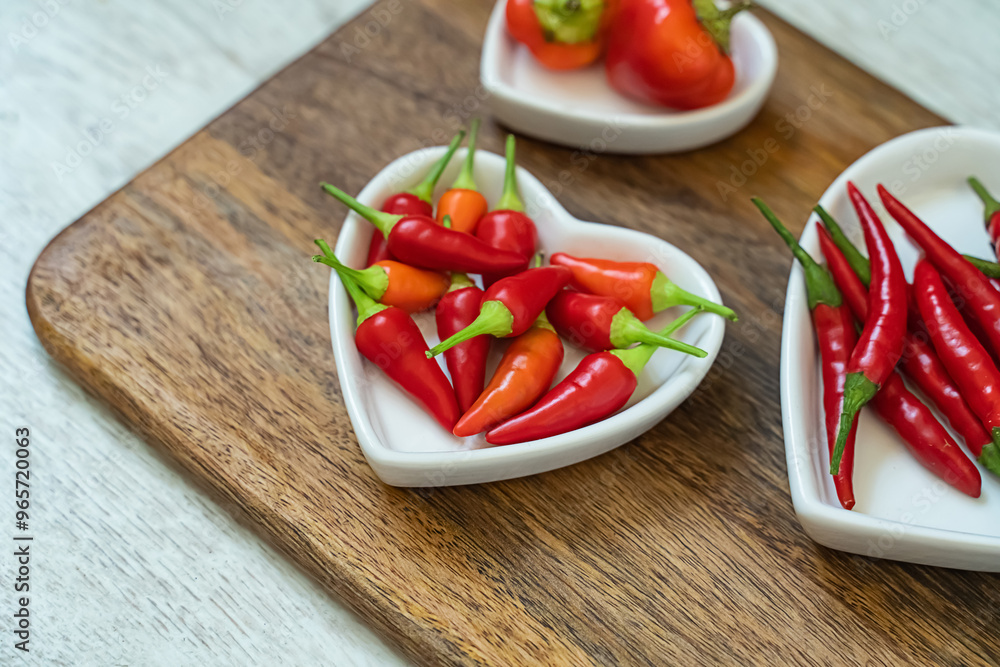 assorted red chili peppers and heart shaped plate set selective focus assorted red chili peppers and heart shaped plate set selective focus