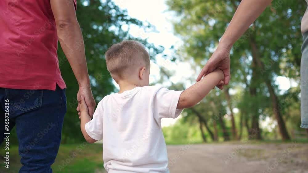happy family in the park. a child walks with his parents holding hands, view from back in park in nature, walking. happy family kid dream concept. child son walking with parents in park sun happy family in the park. a child walks with his parents holding hands, view from back in park in nature, walking. happy family kid dream concept. child son walking with parents in park sun