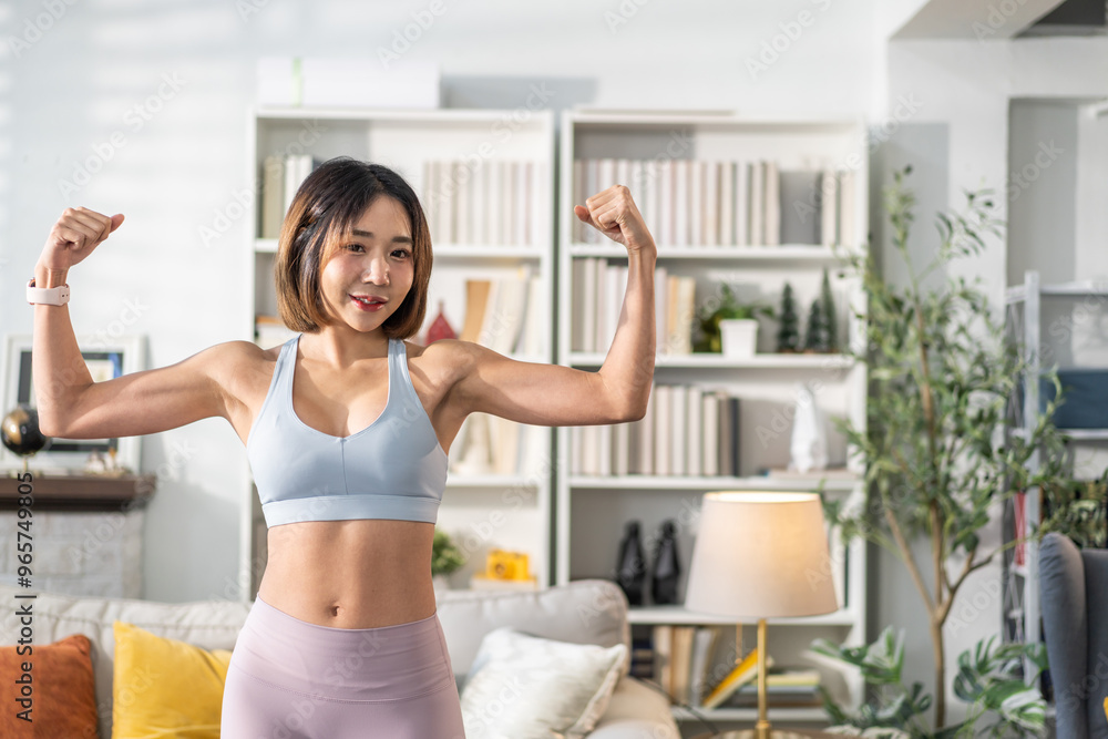 Young woman fitness and healthy lifestyle in her home, confidently flexing arm to show off her toned muscles, strength, determination and self-confidence, wellness and home workouts, fitness routines Young woman fitness and healthy lifestyle in her home, confidently flexing arm to show off her toned muscles, strength, determination and self-confidence, wellness and home workouts, fitness routines