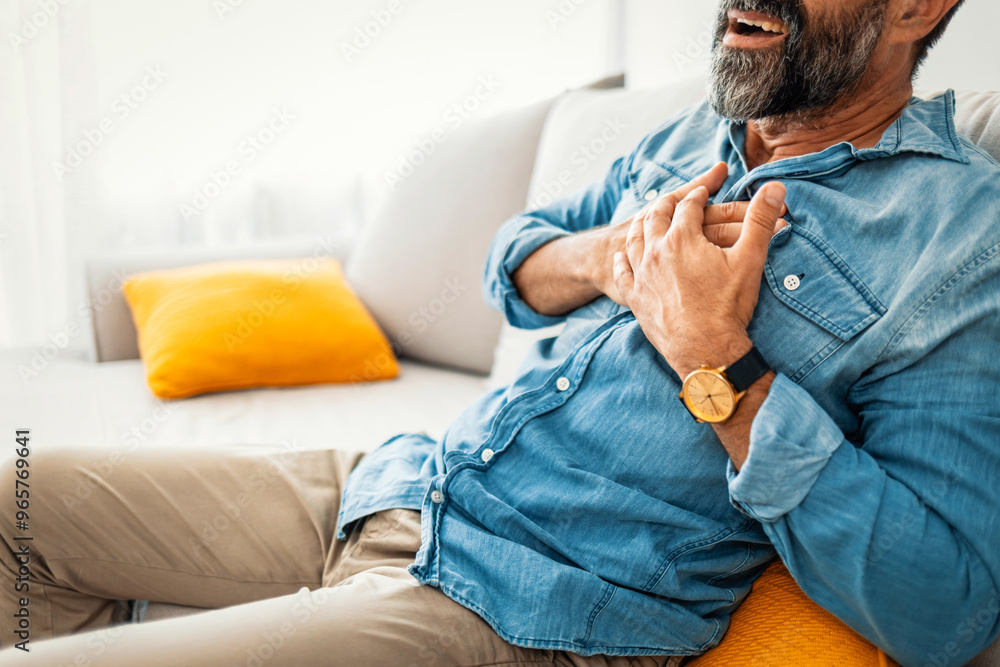 Man Experiencing Chest Pain While Sitting on Couch Man Experiencing Chest Pain While Sitting on Couch